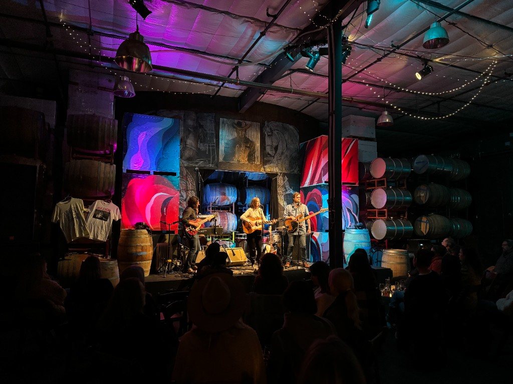 Live band performing on stage in the Standing Sun Wines barrel room