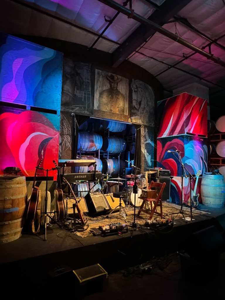 Standing Sun Live stage ready with guitars, murals, and wine barrels